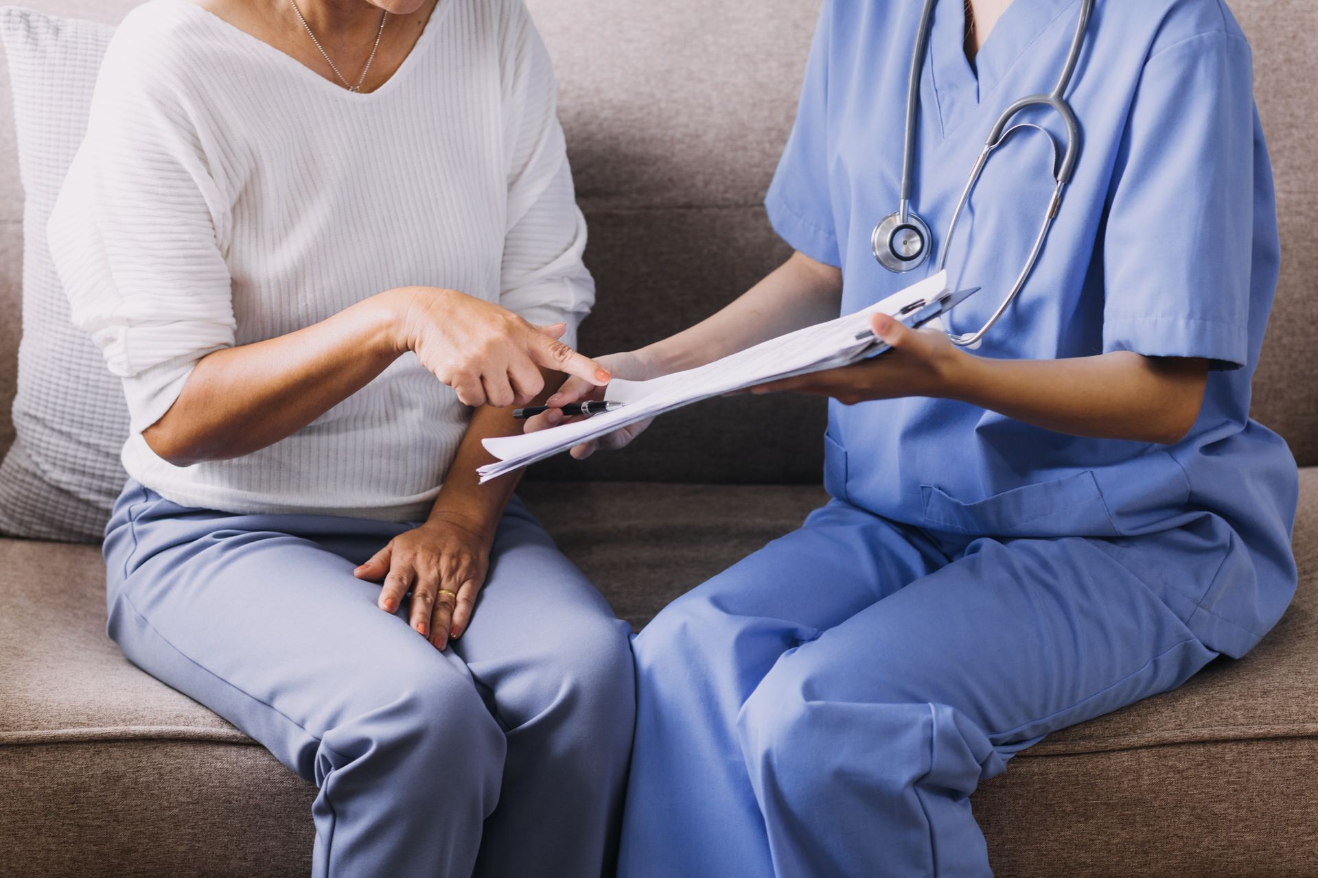 A nurse reviewing paperwork with an older patient at home